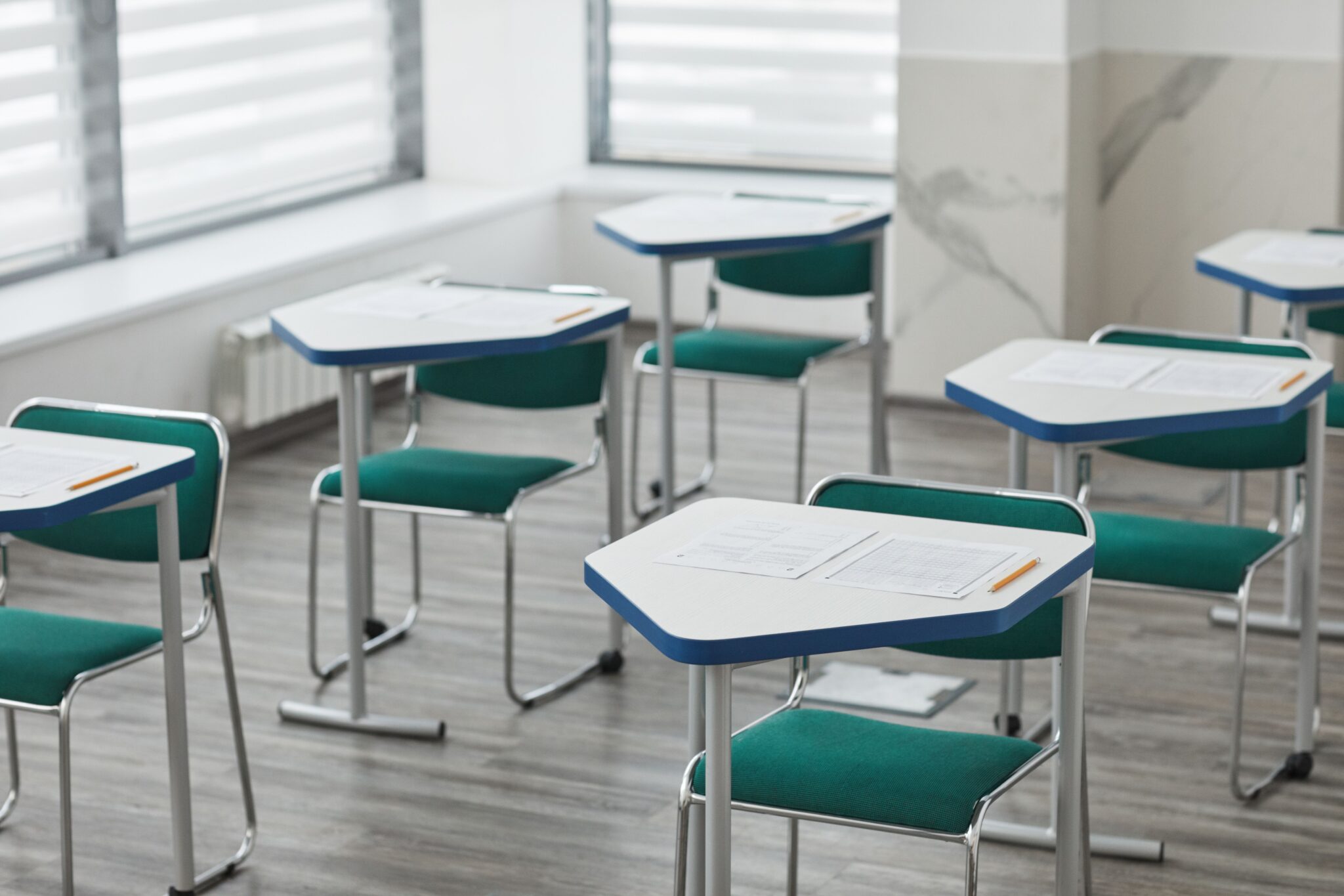 Salle d'examen préparée, tables individuelles espacées, sujets et crayons disposés pour les candidats