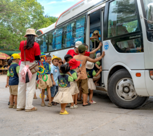 De jeunes élèves en chapeau de soleil montent dans un bus pour une sortie scolaire