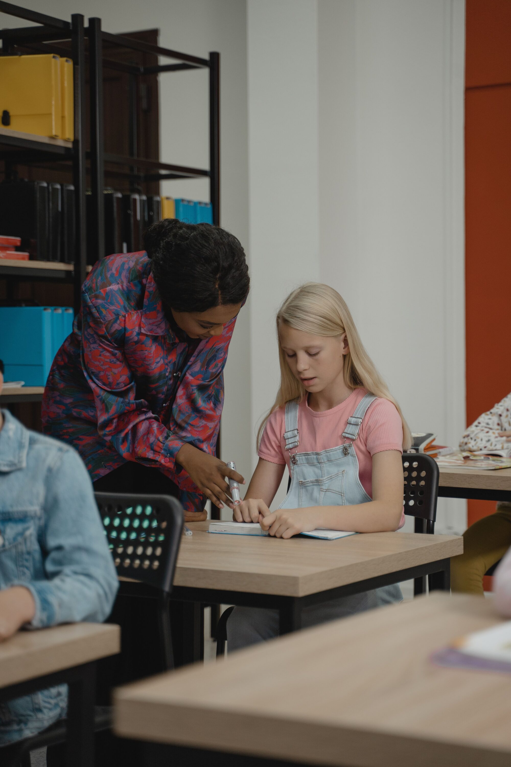 Teacher leaning over a pupil’s desk to give feedback on her work